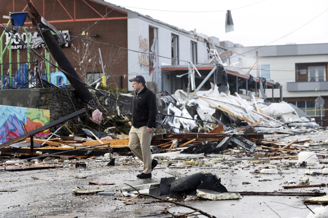 A man walks past storm debris Tuesday, March 3, 2020, in Nashville, Tenn. At least two tornadoes touched down early Tuesday in central Tennessee, including one that ripped across areas near downtown Nashville and caused multiple buildings to collapse. (AP Photo/Mark Humphrey)