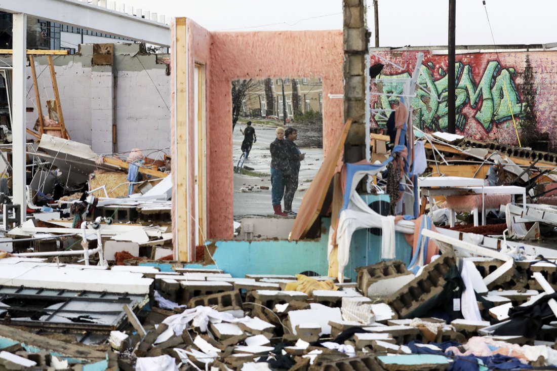 People are reflected in a mirror of a building destroyed by storms Tuesday, March 3, 2020, in Nashville, Tenn. At least two tornadoes touched down early Tuesday in central Tennessee, including one that ripped across areas near downtown Nashville and caused multiple buildings to collapse. (AP Photo/Mark Humphrey)
