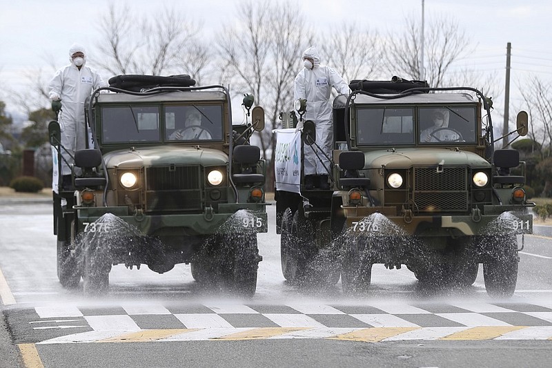 South Korean army trucks spray disinfectant as a precaution against the coronavirus on a street in Ulsan, South Korea, Tuesday, March 3, 2020. China's coronavirus caseload continued to wane Tuesday even as the epidemic took a firmer hold beyond Asia. (Kim Young-tae/Yonhap via AP)