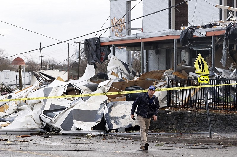 A man walks past storm debris following a deadly tornado, Tuesday, March 3, 2020, in Nashville, Tenn. (AP Photo/Mark Humphrey)