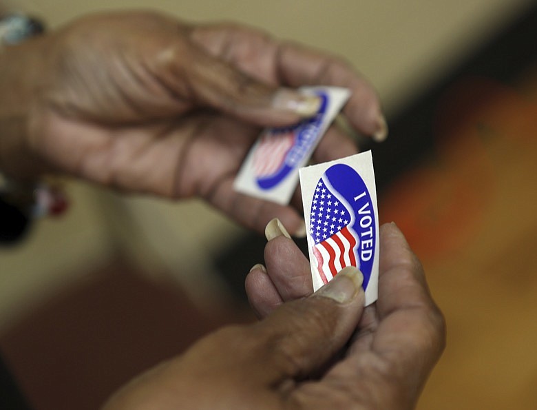 An election officer passes out "I Voted" stickers during the Super Tuesday primary at at Lincoln Terrace Elementary School in Roanoke, Virginia. (Heather Rousseau/The Roanoke Times via AP)