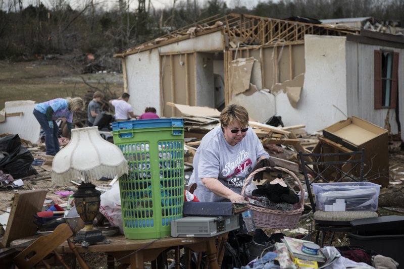 Staff photo by Troy Stolt / Debra Maxwell picks up a water bottle as she works to sort through what remains of her mobile home a day after it was destroyed by a tornado in Cookeville, Tenn. on Wednesday, March 4, 2020. Maxwell said she began to hear the sound of the tornado shortly after heading to sleep around 1pm early Tuesday and decided to run to her boyfriend's home next door, the storm destroyed her mobile home minutes after.
