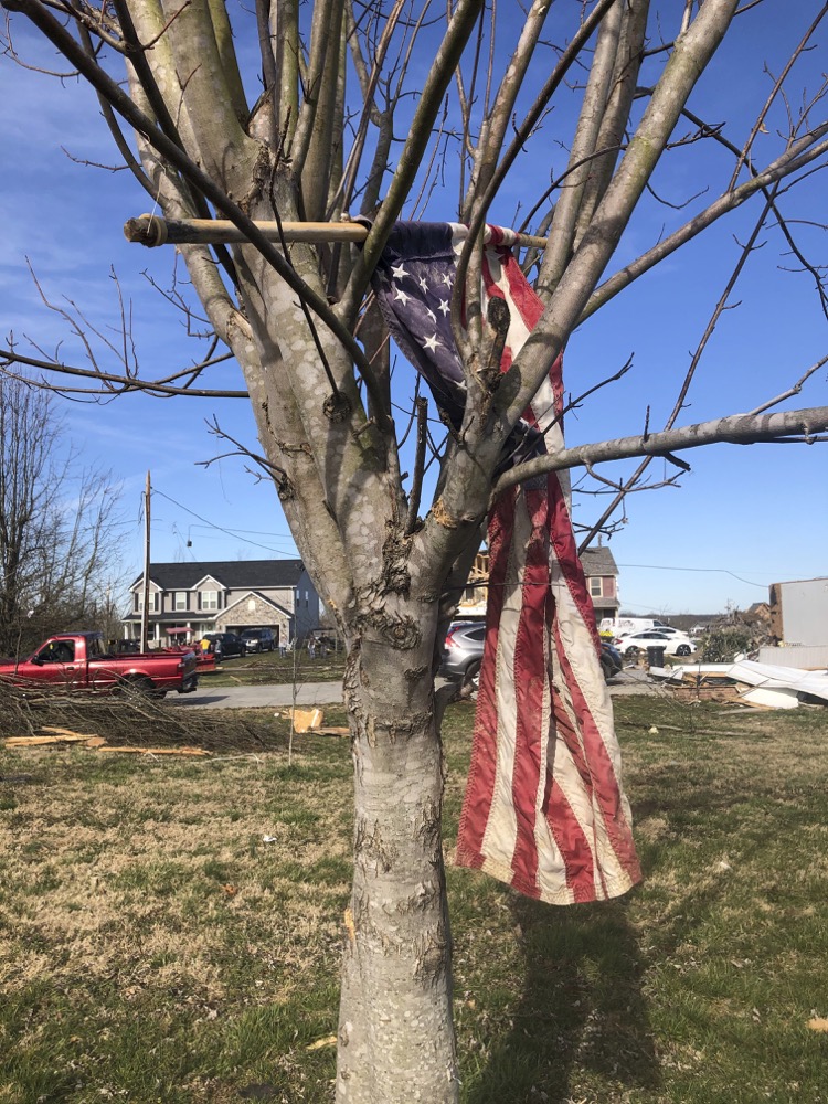 A tattered flag is lodged in a tree on Wednesday, March 4, 2020, after a tornado tore through a Putnam County, Tennessee, neighborhood Tuesday, destroying most of the homes. (AP Photo/Travis Loller)