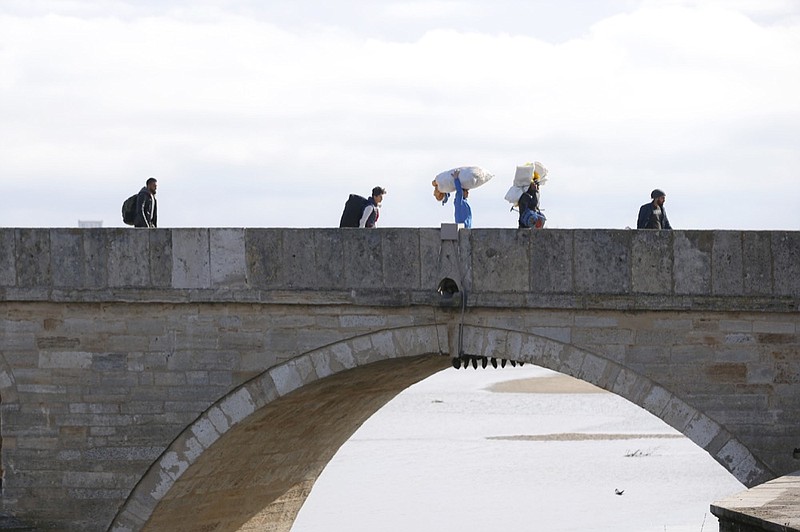 Migrants walk on a bridge in Edirne near the Turkish-Greek border on Thursday, March 5, 2020. Turkey has vowed to seek justice for a migrant it says was killed on the border with Greece after Greek authorities fired tear gas and stun grenades to push back dozens of people attempting to cross over. Greece had denied that anyone was killed in the clashes. (AP Photo/Darko Bandic)

