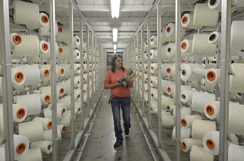 File Photo by Angela Lewis/ Creeler Vickie Glover carries empty spools while seeing which spools need replacing Friday at the Dixie Group in North Georgia.