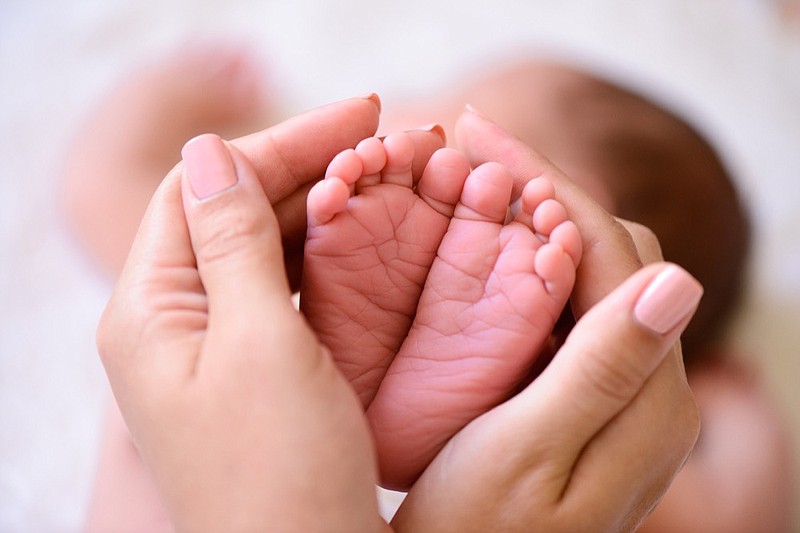 Mother holding tiny foot of newborn baby childbirth tile child tile baby tile parent  / Getty Images 
