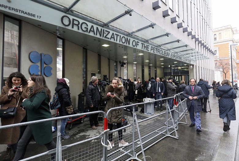 People stand in front of the headquarters of the Organization of the Petroleum Exporting Countries, OPEC, in Vienna, Austria, Friday, March 6, 2020. (AP Photo/Ronald Zak)
