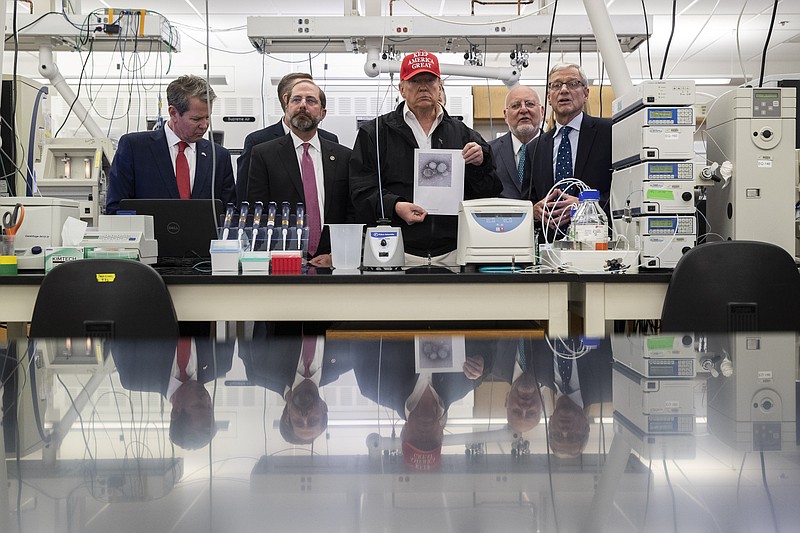 President Donald Trump holds a picture as he speaks during a meeting with Gov. Brian Kemp, R-Ga., left, Health and Human Services Secretary Alex Azar, Centers for Disease Control and Prevention Director Dr. Robert Redfield, Associate Director for Laboratory Science and Safety Steve Monroe, about the coronavirus at the Centers for Disease Control and Prevention Director, Friday, March 6, 2020 in Atlanta. (AP Photo/Alex Brandon)