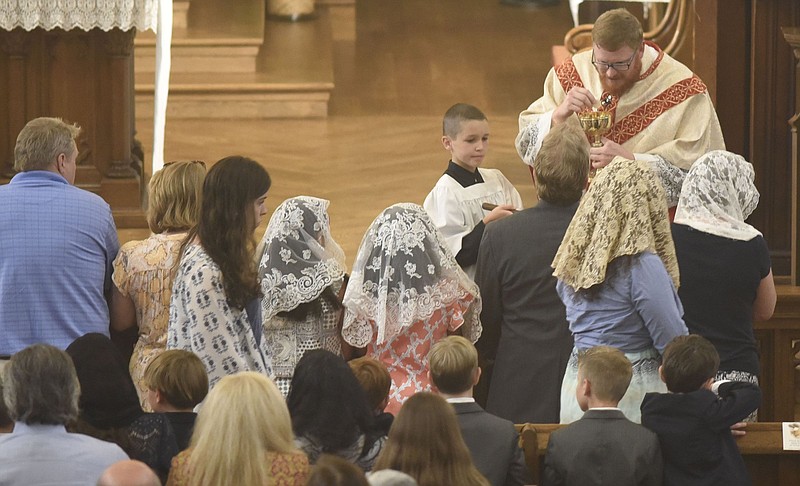 Staff Photo by Robin Rudd / Reverend David Carter, upper right, gives Communion to a communicants during the Feast of Corpus Christi at the Basilica of Saint Peter and Paul on June 23, 2019.  