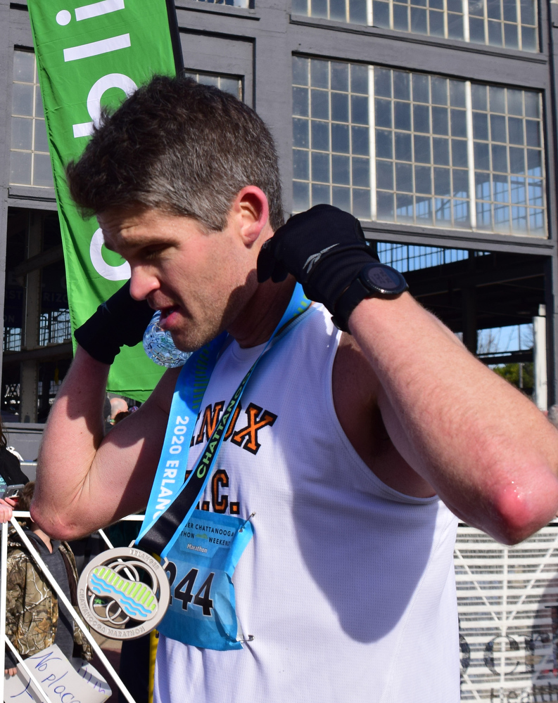Staff Photo by Robin Rudd / Bradley Adams, second place finisher in the marathon puts on his medal. The 5th Erlanger Chattanooga Marathon was run on March 8, 2020.