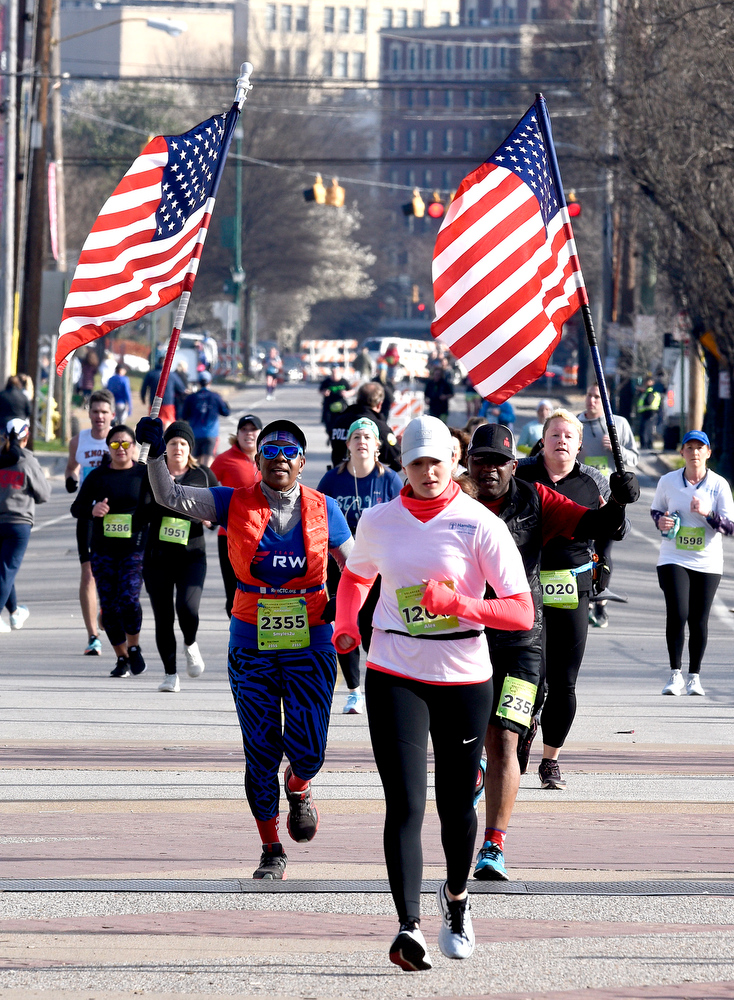 Staff Photo by Robin Rudd / Each carrying a American flag Annette and Danny Tolliver finish just behind Alex Duckett in the half marathon. The 5th Erlanger Chattanooga Marathon was run on March 8, 2020.