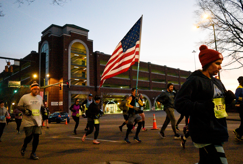 Staff Photo by Robin Rudd / A runner carries a large United States Flag down Market Street during the race. The 5th Erlanger Chattanooga Marathon was run on March 8, 2020.