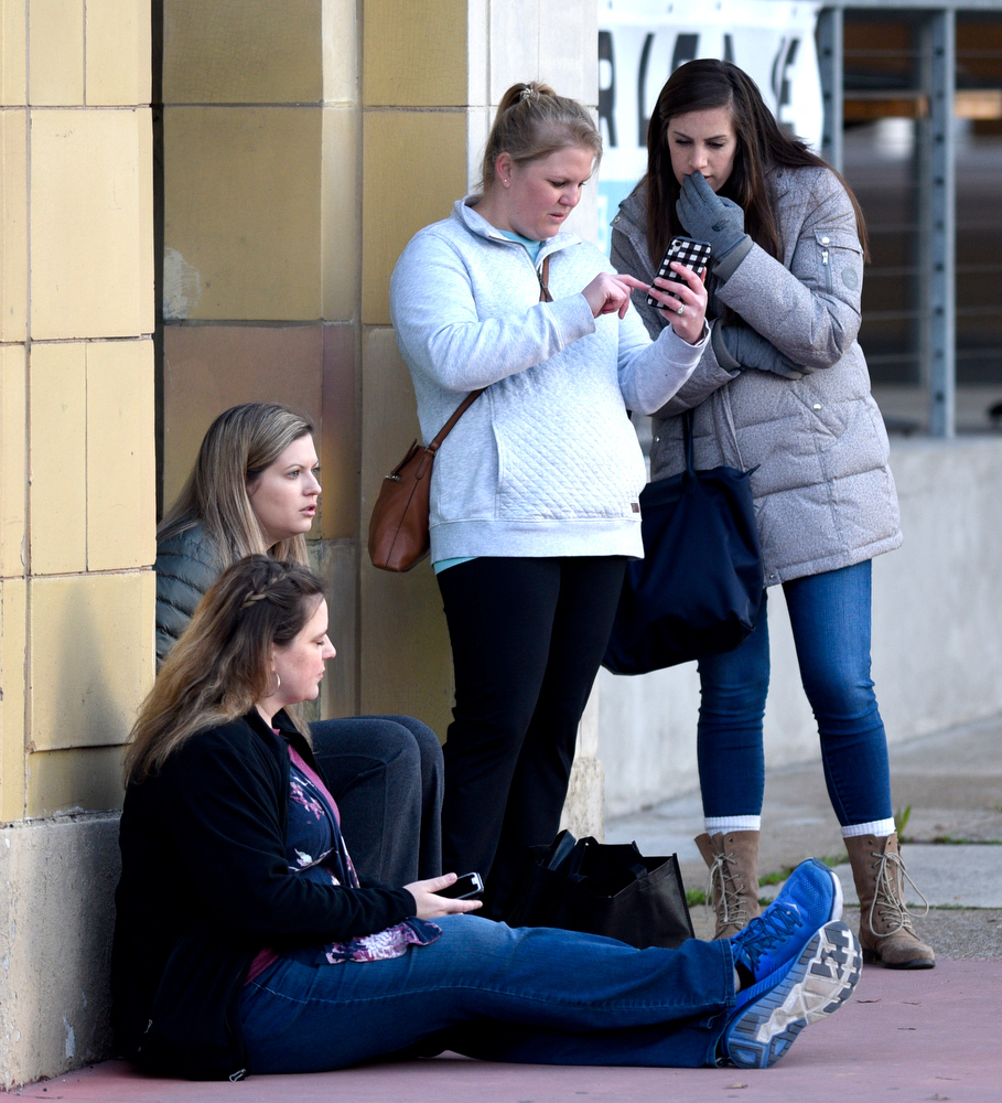 Staff Photo by Robin Rudd / Spectaors check the race app on their phones as they wait at the corner of Martin Luther King Jr. Blvd. and Lindsey Street. The 5th Erlanger Chattanooga Marathon was run on March 8, 2020.
