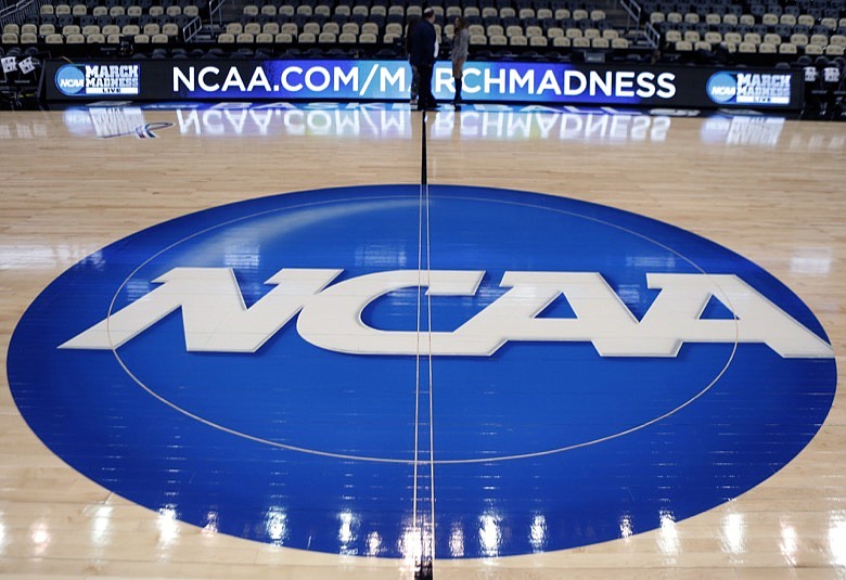 In this March 18, 2015, file photo, the NCAA logo is displayed at center court as work continues at The Consol Energy Center in Pittsburgh, for the NCAA college basketball tournament. The NCAA took a significant step toward allowing all Division I athletes to transfer one time without sitting out a season of competition. A plan to change the waiver process is expected to be presented to the Division I Council in April, 2020. If adopted, new criteria would go into effect for the 2020-21 academic year and be a boon for athletes in high-profile sports such as football and men's and women's basketball. (AP Photo/Keith Srakocic, File)