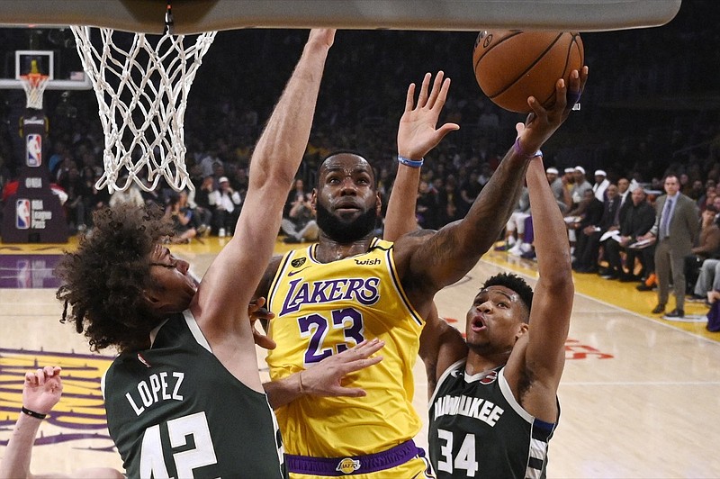 Los Angeles Lakers forward LeBron James, center, shoots as Milwaukee Bucks center Robin Lopez, left, and forward Giannis Antetokounmpo defend during the first half of an NBA basketball game Friday, March 6, 2020, in Los Angeles. (AP Photo/Mark J. Terrill)