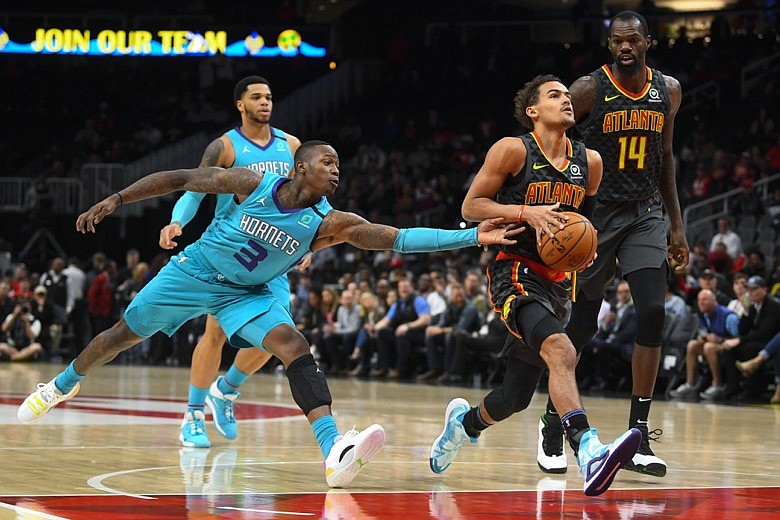 Atlanta Hawks guard Trae Young, front right, drives the lane as Charlotte Hornets guard Terry Rozier (3) defends during the first half of an NBA basketball game Monday, March 9, 2020, in Atlanta. (AP Photo/John Amis)