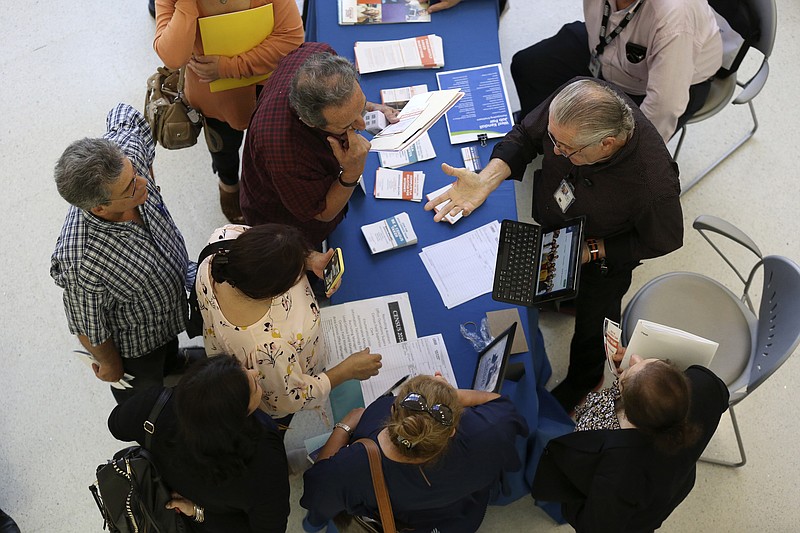 FILE - In this Sept. 18, 2019 file photo, Alex Pereira, of the U.S. Census Bureau, right, talks with job applicants about temporary positions available with the 2020 Census, during a job fair designed for people fifty years or older, in Miami. The U.S. Census Bureau said it has reached its goal of recruiting more than 2.6 million applicants for the once-a-decade head count that launched for most of America this week — but it has been a bumpy road getting there. (AP Photo/Lynne Sladky, File)