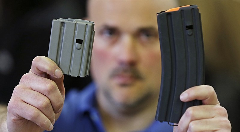 In this April 10, 2013 file photo, Jonathan Scalise, owner of Ammunition Storage Components, holds up a 10-round, left, and a 30-round magazine that his company manufacturers for the AR-15 rifle in New Britain, Conn. Gun rights supporters are suing Connecticut officials over part of a 2013 state gun control law passed after the Sandy Hook school shooting, saying it unconstitutionally bans people from loading more than 10 rounds of ammunition into their firearms. The lawsuit filed in U.S. District Court on Tuesday, March 10, 2020 cites the Second Amendment right to bear arms and the ability of people to better defend themselves with more bullets in their guns. (AP Photo/Charles Krupa, File)