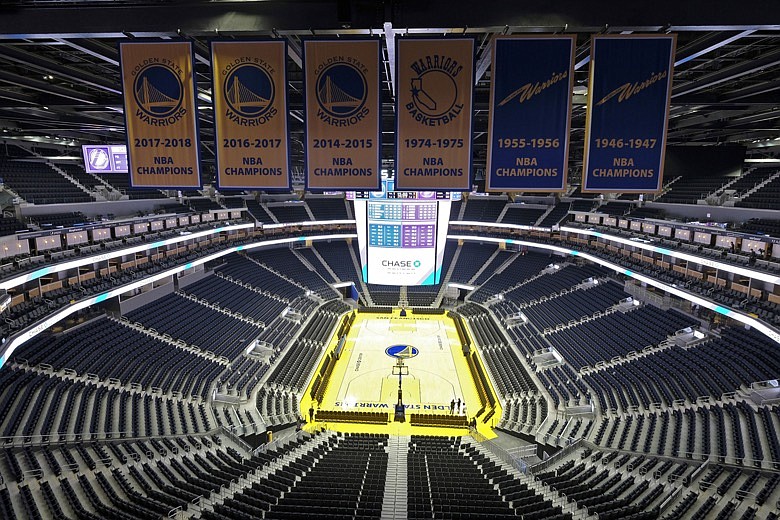 In this Aug. 26, 2019, file photo, the Golden State Warriors championship banners hang above the seating and basketball court at the Chase Center in San Francisco. The Warriors will play the Brooklyn Nets at home Thursday night, March 12, 2020, in the first NBA game without fans since the outbreak of the coronavirus. (AP Photo/Eric Risberg, File)