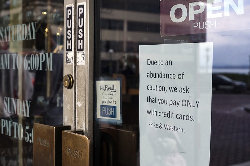 A sign posted on a door at a store near Pike Place Market, an area tourist attraction, requests credit card payments only, Wednesday, March 11, 2020, in Seattle. In efforts to slow the spread of the new coronavirus, Washington state Gov. Jay Inslee announced a ban on large public gatherings in three counties in the metro Seattle area. (AP Photo/Stephen Brashear)


