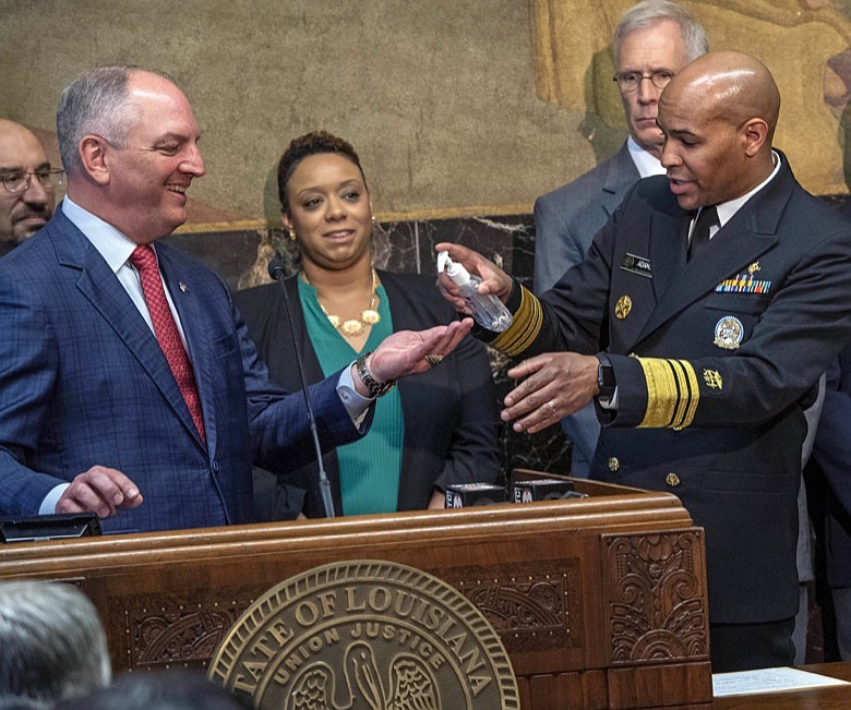 U.S. Surgeon General VADM Jerome M. Adams, M.D., M.P.H., right, squirts hand sanitizer into Gov. John Bel Edwards, left, palm as the pair talk about the coronavirus at a press conference at the state capital Thursday March 12, 2020, in Baton Rouge, La. (Bill Feig/The Advocate via AP)