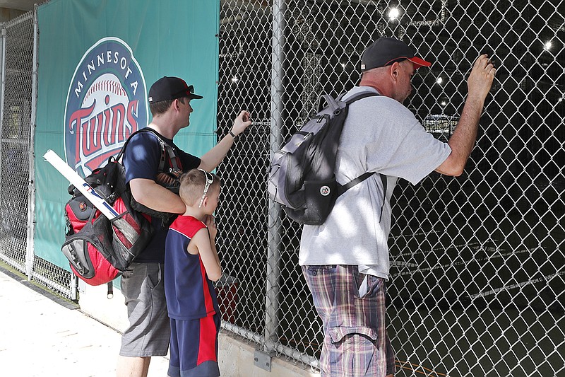 AP photo by Elise Amendola / Fans look through a fence at Hammond Stadium after a spring training exhibition game between the Minnesota Twins and the Baltimore Orioles was canceled on Thursday in Fort Myers, Fla. Major League Baseball suspended the rest of its spring training game schedule because of the coronavirus outbreak. MLB is also delaying the start of its regular season by at least two weeks.