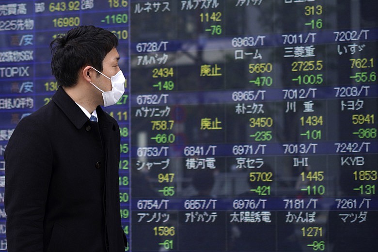 A man looks at an electronic stock board showing Japan's Nikkei 225 index at a securities firm in Tokyo Friday, March 13, 2020. Shares have plunged in Asia, with Japan's benchmark sinking 10% after Wall Street suffered its biggest drop since the Black Monday crash of 1987. (AP Photo/Eugene Hoshiko)