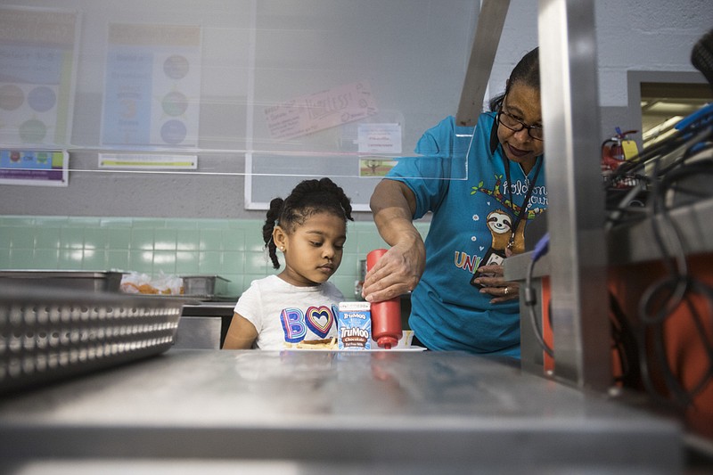  Staff photo by Troy Stolt / Lee Elder pours ketchup onto Pre K student Nivayeh O'neal's plate at Rivermont elementary school on Friday, March 13, 2020 in Chattanooga, Tenn.