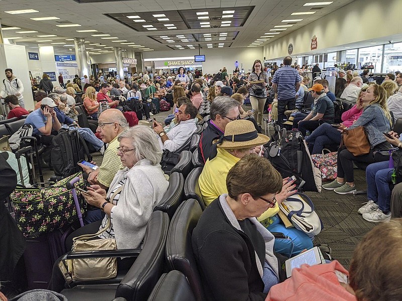 A gate area at Fort Lauderdale-Hollywood International Airport is crowded with travelers awaiting Delta flight 1420 to Atlanta Saturday, March 14, 2020. Weary travelers returning to the U.S. amid coronavirus-related travel restrictions are being greeted by long lines and hourslong waits for required medical screenings at airports. (AP Photo/John Scalzi)