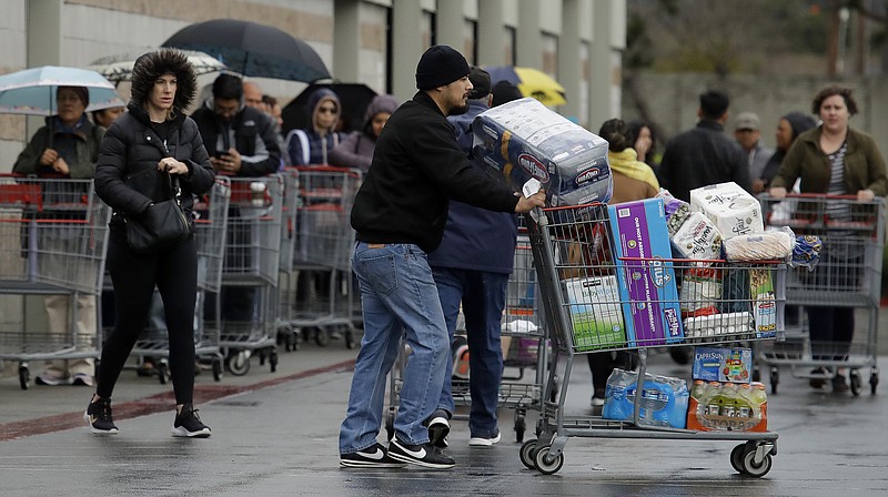 The Associated Press / Costco customers roll filled groceries to their cars Saturday in San Leandro, California, leaving empty shelves and needy customers.