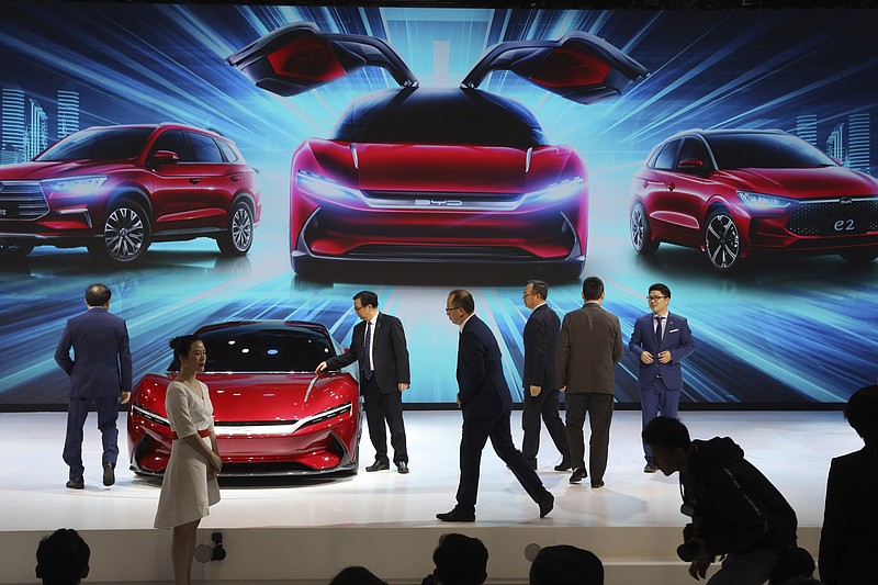 FILE - In this April 16, 2019, file photo, attendees take a close look at cars from BYD at the Auto Shanghai 2019 show in Shanghai. China's auto sales plunged 81.7% in February, 2020, from a year ago after Beijing shut down much of the economy to fight a virus outbreak, adding to problems for an industry that already was struggling with shrinking demand. (AP Photo/Ng Han Guan, File)

