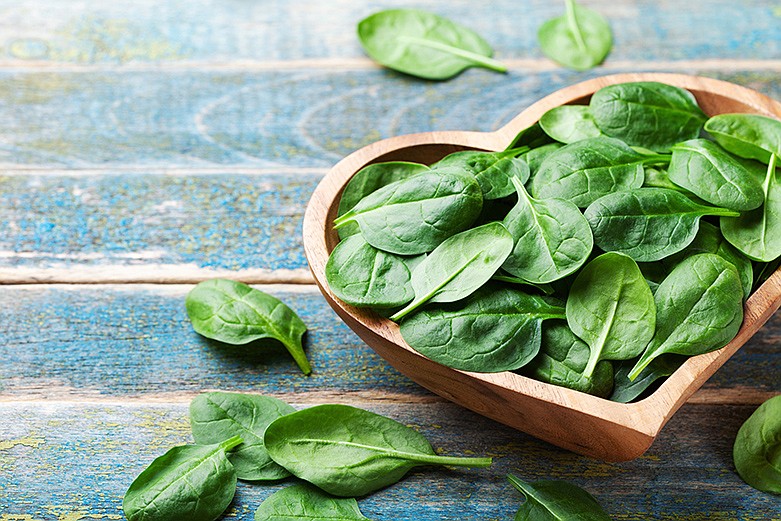 Baby spinach leaves in bowl on rustic wooden table. / Getty Images/iStockphoto/Julia_Sudnitskaya