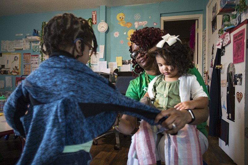 Staff photo by Troy Stolt / Kathryn Gladden, owner and operator of Tweety's Child Care Home, helps Levi Morgan, 3, put his jacket on as 2-year-old Eastyn Hildreth sits on her lap on Tuesday, March 17, 2020 in Chattanooga, Tenn. With Hamilton County schools and many businesses closed, early child care providers are left grappling with a hard decision of whether they should close down to protect their employees and children from the spread of the coronavirus (COVID-19), or stay open for families who have no other options.