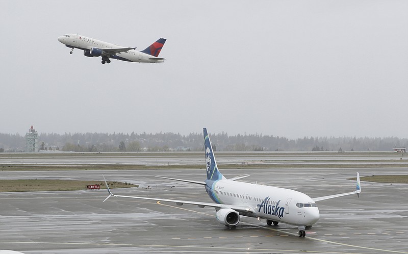 FILE - In this April 13, 2018 file photo, a Delta Air Lines plane takes off above a taxiing Alaska Airlines airplane at the Seattle-Tacoma International Airport in Seattle. (AP Photo/Ted S. Warren, File)


