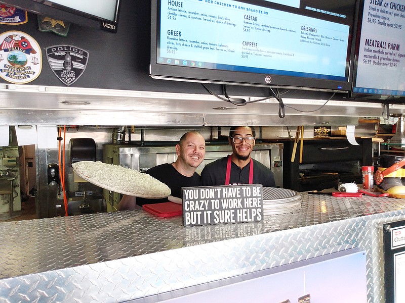 Photo by Jay Greeson / Erik Clien, left, owner of New York Pizza Department, and Tyler Glover prepare pizzas to give free to students who are missing lunches since schools have been closed.