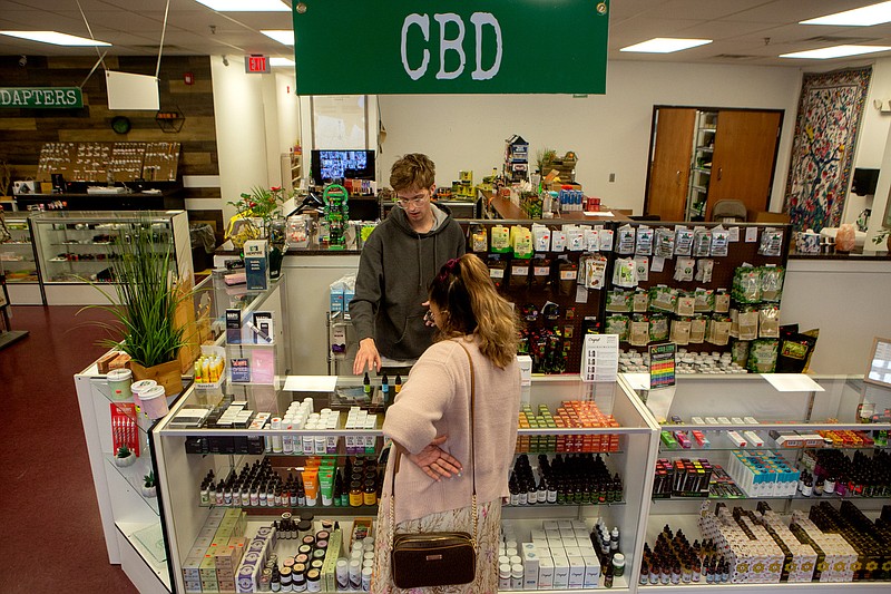 Staff photo by C.B. Schmelter / Jackson Case, top, helps Bri Fears pick out CBD products at Grass Roots Health on Wednesday, March 18, 2020, in Chattanooga. Grass Roots Health is seeing double its normal sales.