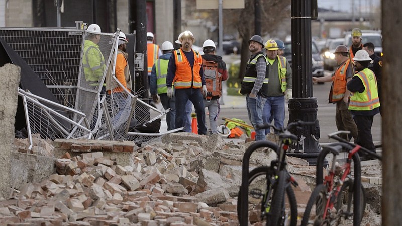 Construction workers looks at the rubble from a building after an earthquake Wednesday, March 18, 2020, in Salt Lake City. A 5.7-magnitude earthquake has shaken the city and many of its suburbs. The quake sent panicked residents running to the streets, knocked out power to tens of thousands of homes and closed the city's airport and its light rail system.  (AP Photo/Rick Bowmer)


