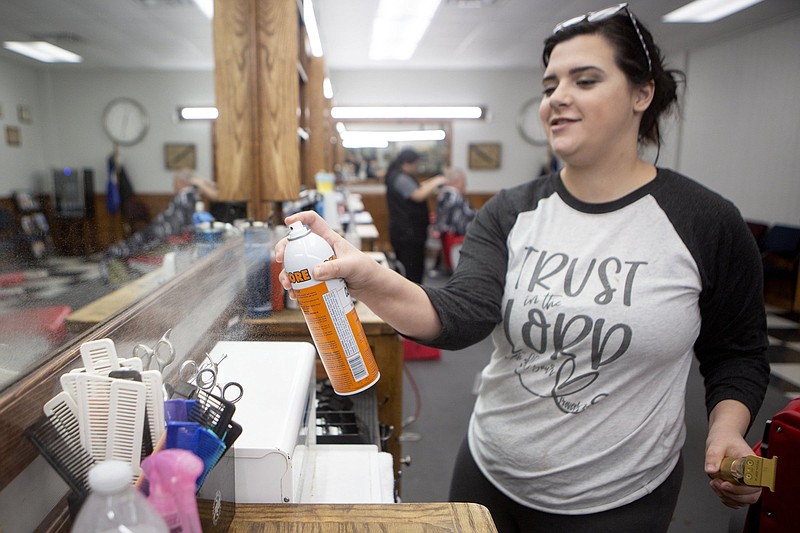 Staff photo by C.B. Schmelter / Bailey Norrod sprays a disinfectant after cutting a client's hair at White Oak Barber Shop's Lee Highway location on Tuesday, March 17, 2020 in Chattanooga, Tennessee. White Oak Barber Shop shortened their hours because of the decline in customers due to the coronavirus pandemic. The barber shop is also taking extra precautions for customers like using fresh capes for each hair cut.