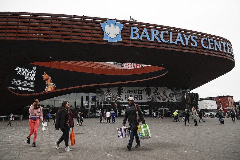 AP photo by John Minchillo / People walk past the Barclays Center, which is home to the Brooklyn Nets, on March 12. Five days later, the Nets announced that four of their players had tested positive for the new coronavirus, bringing the total to seven known players in the NBA.