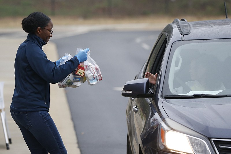 Volunteer Michaela Lawrence hands out meals to families with students at Hilsman Middle School in Athens, Ga., on Tuesday, March 17, 2020. Meals will be handed out each morning from 8:00a.m. to 10:00p.m. at Hilsman Middle School in Oglethorpe Elementary as well as others delivered by bus due to caronavirus. (Joshua L. Jones/Athens Banner-Herald via AP)