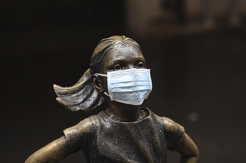 A surgical mask is placed on The "Fearless Girl" statue outside the New York Stock Exchange on Thursday, March 19, 2020, in New York. Stocks are swinging between gains and losses in early trading on Wall Street Thursday, but the moves are more subdued than the wild jabs that have dominated recent weeks. (AP Photo/Kevin Hagen)


