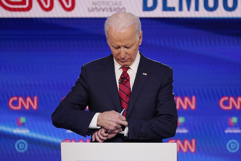 Former Vice President Joe Biden, check his watch during a commercial break as he participates in a Democratic presidential primary debate at CNN Studios, Sunday, March 15, 2020, in Washington. (AP Photo/Evan Vucci)