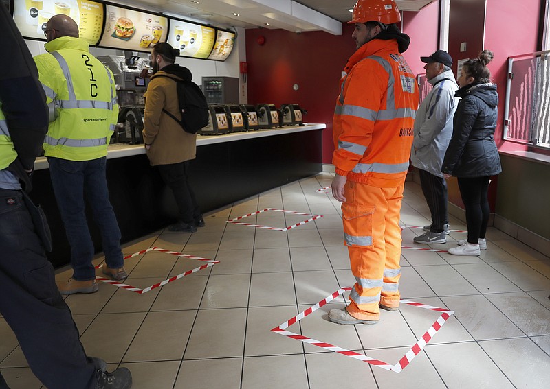People stand in marked places to keep a social distance at a fast food restaurant in London, Friday, March 20, 2020. For most people, the new coronavirus causes only mild or moderate symptoms, such as fever and cough. For some, especially older adults and people with existing health problems, it can cause more severe illness, including pneumonia. (AP Photo/Frank Augstein)


