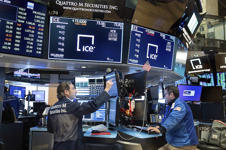 In this photo provided by the New York Stock Exchange, traders John Romolo, left, and Leon Montana work on the trading floor on Friday, March 20, 2020. Stocks turned lower Friday after New York became the latest major state to mandate nearly all workers stay home to limit the spread of the new coronavirus. (Nicole Pereira/NYSE via AP)