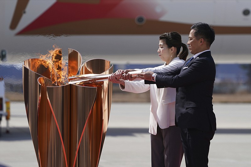 Three-time Olympic gold medalists Tadahiro Nomura, right, and Saori Yoshida light the torch during Olympic Flame Arrival Ceremony at Japan Air Self-Defense Force Matsushima Base in Higashimatsushima in Miyagi Prefecture, north of Tokyo, Friday, March 20, 2020. The Olympic flame from Greece arrived in Japan even as the opening of the the Tokyo Games in four months is in doubt with more voices suggesting the games should to be postponed or canceled because of the worldwide virus pandemic. (AP Photo/Eugene Hoshiko)



