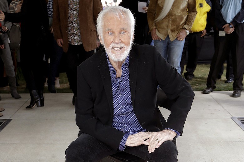 In this Oct. 24, 2017 file photo, Kenny Rogers poses with his star on the Music City Walk of Fame in Nashville, Tenn. Actor-singer Kenny Rogers, the smooth, Grammy-winning balladeer who spanned jazz, folk, country and pop with such hits as "Lucille," "Lady" and "Islands in the Stream" and embraced his persona as "The Gambler" on record and on TV died Friday night, March 20, 2020. He was 81. (AP Photo/Mark Humphrey, File)