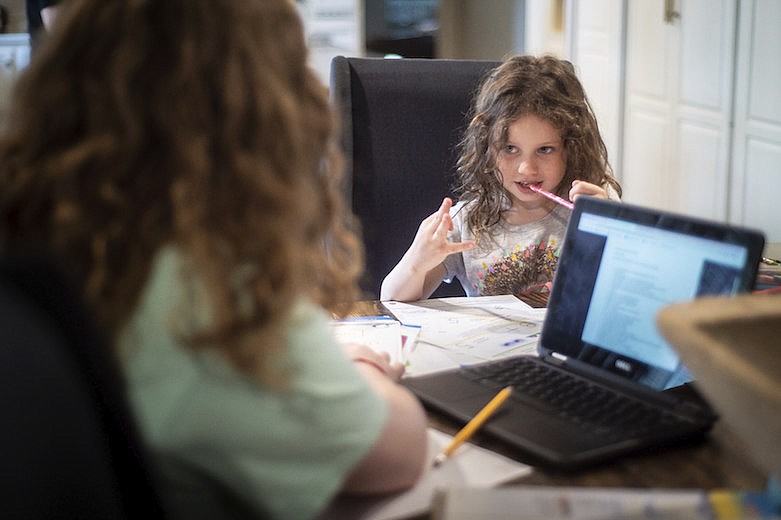 Hunter Reeves, 5, right, an elementary student, gets help from her sister Maysen Reeves, 14, a middle school student, on a math problem as they continue their education at their home Friday, March 20, 2020, in Decatur, Ala. (Dan Busey/The Decatur Daily via AP)