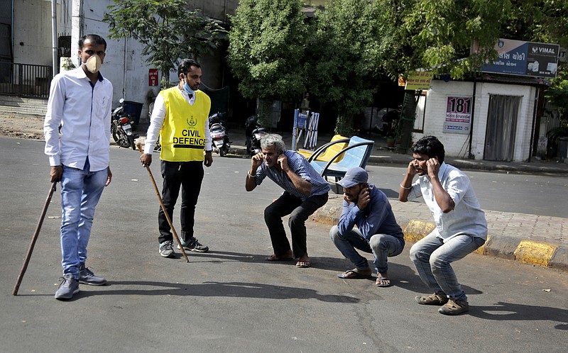 An Indian policeman, left and a civil defense person, second left, make people perform sit ups while holding their ear lobes, as a punishment for stepping out without a valid reason during a lockdown in Ahmedabad, India, Tuesday, March 24, 2020. Authorities have gradually started to shutdown much of the country of 1.3 billion people to contain the outbreak. For most people, the new coronavirus causes only mild or moderate symptoms. For some it can cause more severe illness. (AP Photo/Ajit Solanki)


