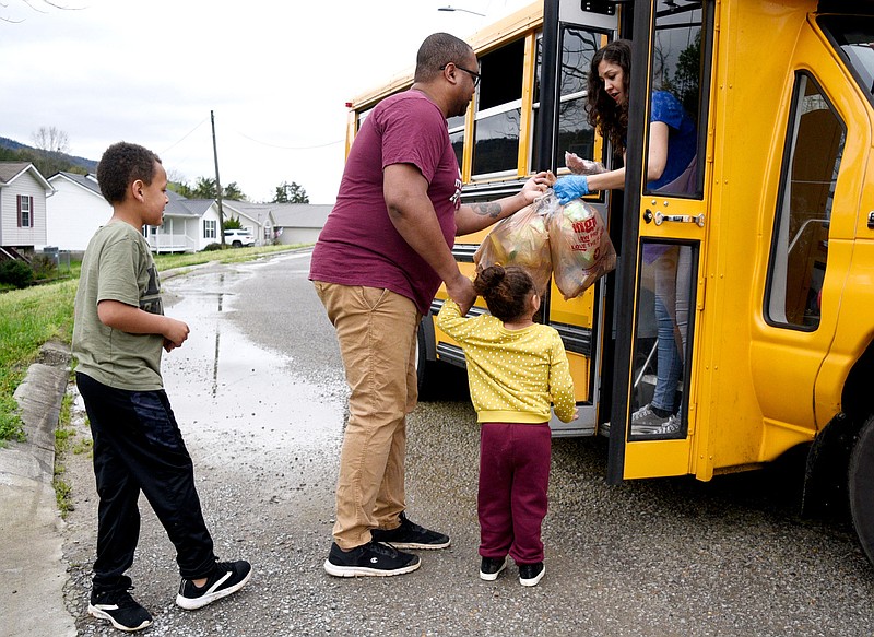 Staff Photo by Robin Rudd / School bus driver Melisa Giles makes a delivery to Chris Dee and his children Patty and Malachi.  Dade County Schools are delivering meals to students by bus at least twice a week while kids are out of town. 