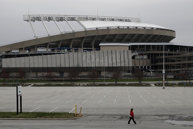 AP photo by Charlie Riedel / A woman walks past Kauffman Stadium, home of the Kansas City Royals, on Wednesday. The start of MLB's regular season is on hold indefinitely because of the coronavirus pandemic.